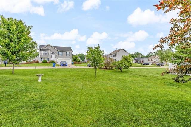 view of green lawn with a garage and driveway