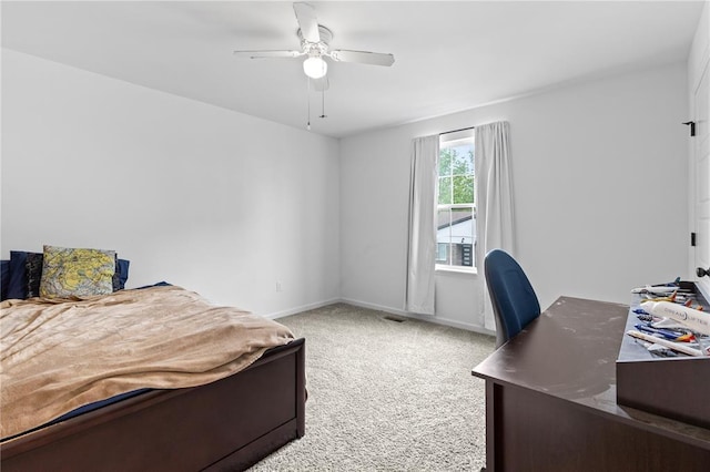 carpeted bedroom with an office area, baseboards, and a ceiling fan