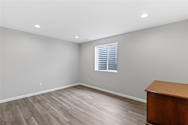 empty room featuring wood finished floors, baseboards, and recessed lighting