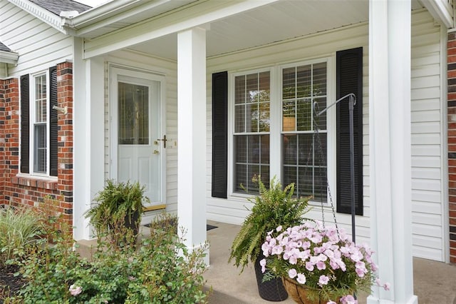 property entrance with covered porch and brick siding