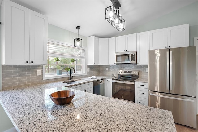 kitchen featuring appliances with stainless steel finishes, a sink, white cabinetry, and light stone countertops