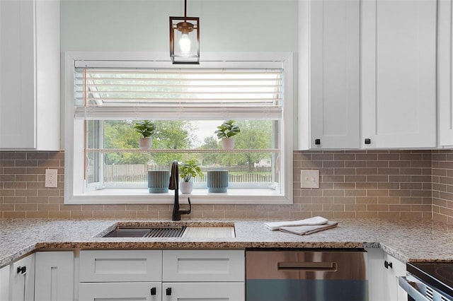 kitchen featuring dishwasher, a sink, white cabinets, and plenty of natural light