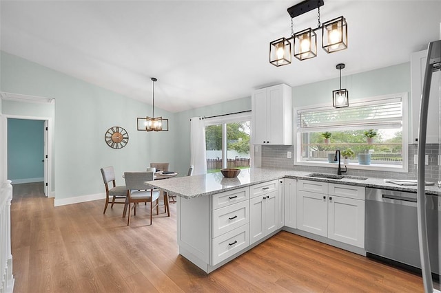 kitchen with a sink, dishwasher, lofted ceiling, decorative backsplash, and a peninsula