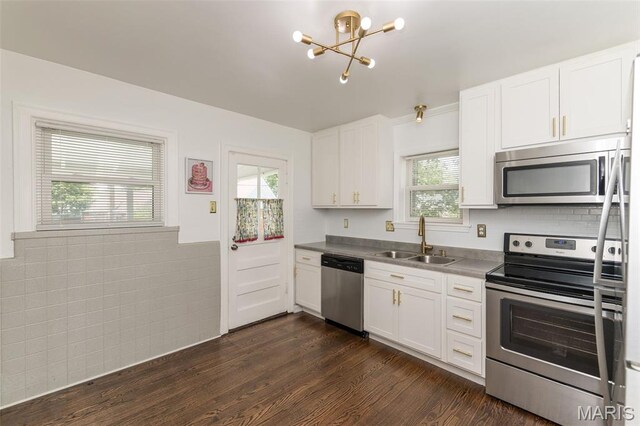 2235 Brown Rd, Overland, MO 63114 - kitchen featuring stainless steel appliances, a chandelier, white cabinets, dark wood-style floors, and a wainscoted wall