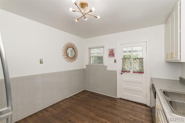 2235 Brown Rd, Overland, MO 63114 - kitchen with a chandelier, white cabinetry, a wainscoted wall, stainless steel dishwasher, and dark wood-type flooring