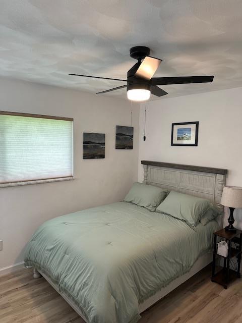 bedroom with wood finished floors, ceiling fan, and baseboards