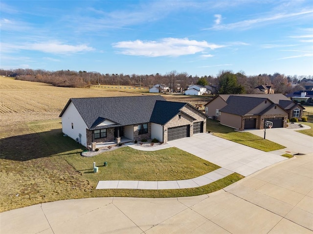 view of front of property featuring an attached garage, concrete driveway, a front yard, stone siding, and a residential view