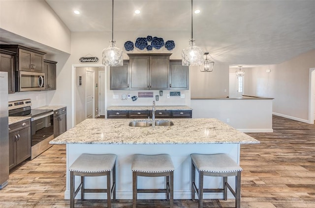 kitchen with stainless steel appliances, a sink, light wood-type flooring, a breakfast bar, and recessed lighting
