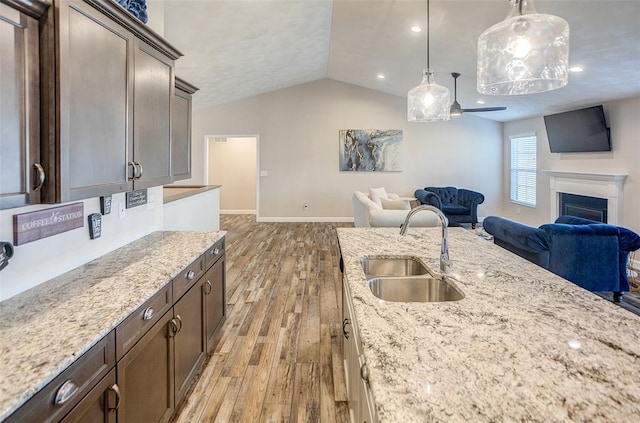 kitchen featuring a sink, open floor plan, light wood-style floors, lofted ceiling, and a ceiling fan