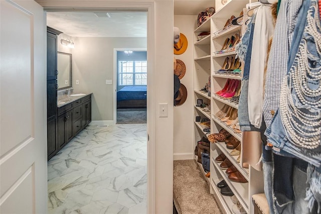 walk in closet featuring light marble finish floors and a sink