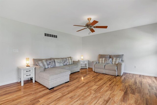 living room featuring a ceiling fan, light wood finished floors, and baseboards