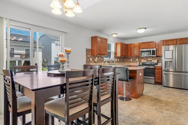 kitchen with appliances with stainless steel finishes, a chandelier, tasteful backsplash, and healthy amount of natural light