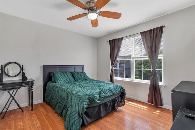 bedroom with light wood-type flooring, baseboards, and ceiling fan