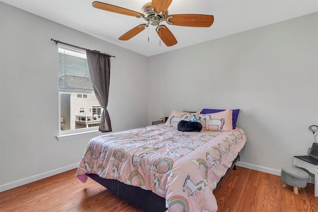 bedroom featuring baseboards, wood finished floors, and ceiling fan