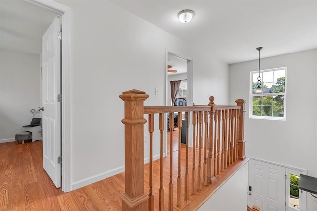 hall featuring an upstairs landing, light wood finished floors, and baseboards