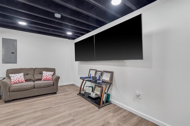 living area with electric panel, light wood-style flooring, and baseboards