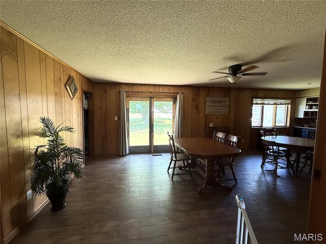 7526 State Highway 164, Cardwell, MO 63829 - dining area featuring a ceiling fan, a textured ceiling, dark wood-style flooring, and wooden walls