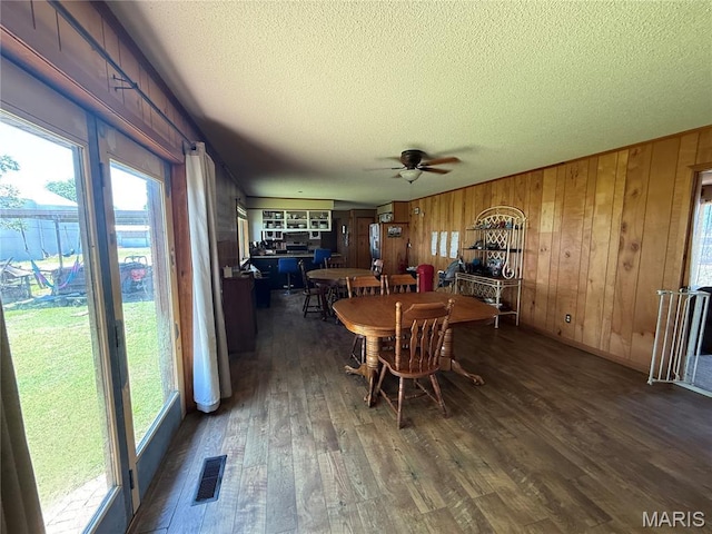 7526 State Highway 164, Cardwell, MO 63829 - dining area featuring a textured ceiling, dark wood-style flooring, plenty of natural light, a ceiling fan, and wooden walls