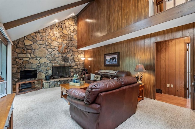carpeted living area with beam ceiling, a stone fireplace, wooden walls, and high vaulted ceiling