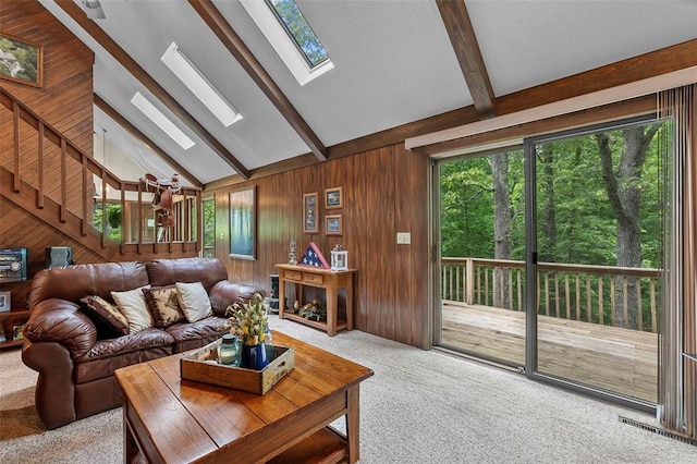 living area with a skylight, beamed ceiling, carpet, wood walls, and high vaulted ceiling