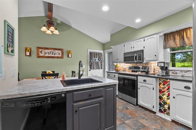 kitchen with stainless steel appliances, a sink, white cabinets, decorative backsplash, and dark stone finish flooring