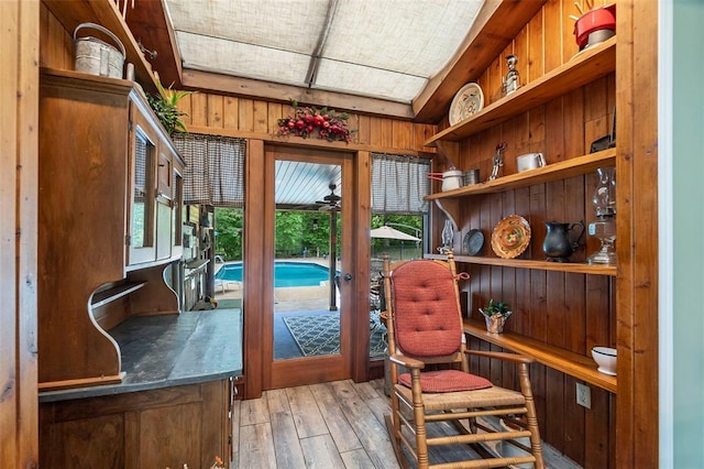 sitting room featuring wooden walls, light wood-type flooring, and french doors
