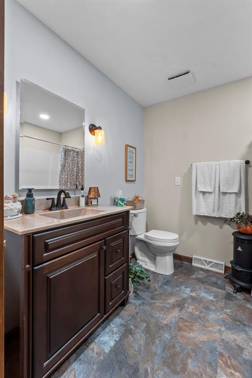 full bath featuring toilet, vanity, baseboards, and a shower with shower curtain