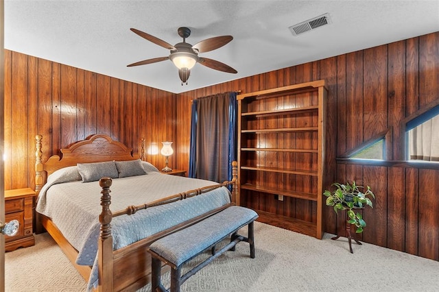 carpeted bedroom with wood walls and ceiling fan