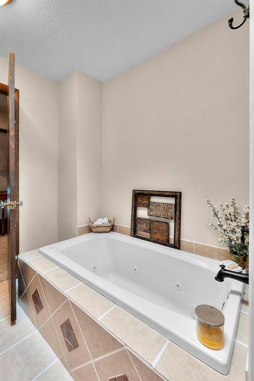 bathroom featuring tile patterned flooring, a whirlpool tub, and a textured ceiling