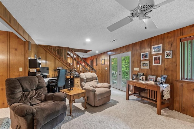 living area with wood walls, an office area, stairway, light carpet, and a textured ceiling