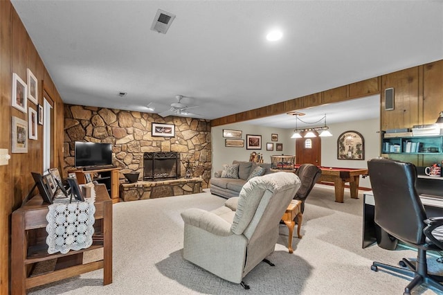 living area featuring billiards, a ceiling fan, wooden walls, light colored carpet, and a stone fireplace