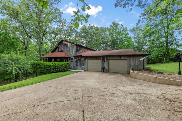view of front of house with an attached garage, concrete driveway, a front yard, and a chimney