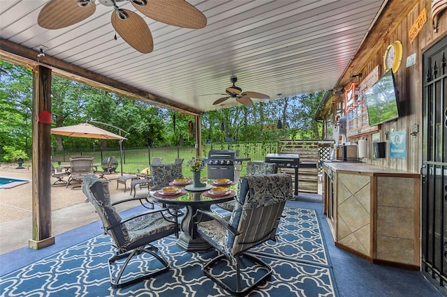 view of patio / terrace with ceiling fan, outdoor dining space, grilling area, view of scattered trees, and fence