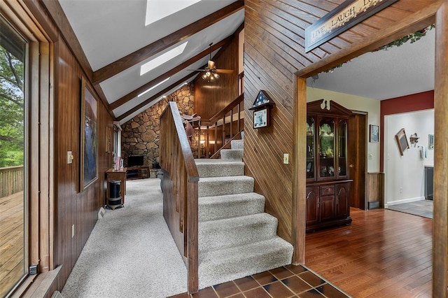 staircase featuring a skylight, wood walls, and ceiling fan
