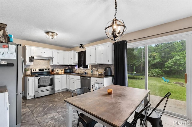 1414 Rue Camille, Bonne Terre, MO 63628 - kitchen with stainless steel appliances, under cabinet range hood, dark marble finish floors, dark countertops, and a chandelier