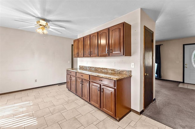 226 Ridgeview Dr, Columbia, IL 62236 - kitchen featuring ceiling fan, baseboards, light stone counters, and brown cabinetry