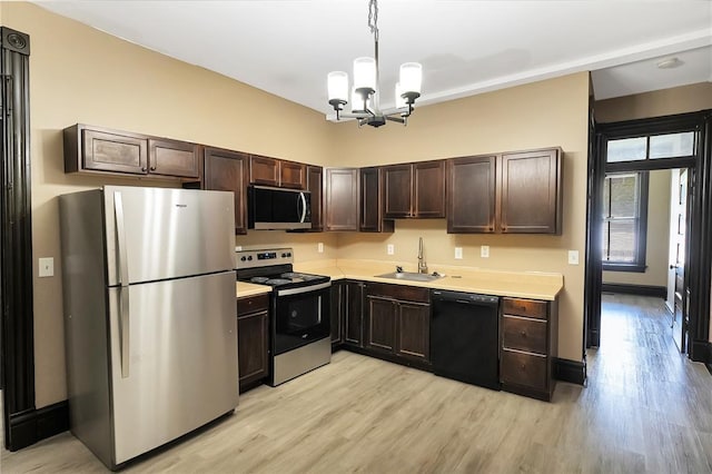 4541 Oakland Ave, Saint Louis, MO 63115 - kitchen with stainless steel appliances, a sink, light wood-style flooring, light countertops, and a chandelier