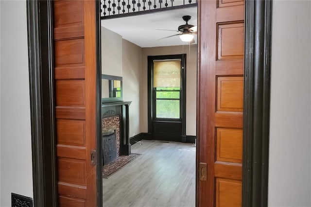 4541 Oakland Ave, Saint Louis, MO 63115 - doorway featuring a fireplace with flush hearth, a ceiling fan, light wood-style floors, and baseboards