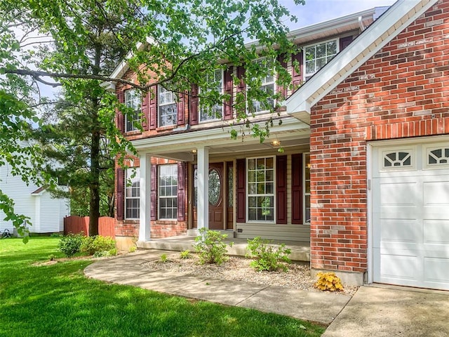 property entrance featuring brick siding, a porch, a yard, and a garage