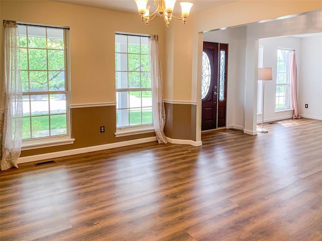 doorway with plenty of natural light, a chandelier, dark wood-style flooring, and baseboards