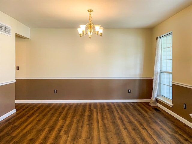 empty room with wood finished floors, a chandelier, and plenty of natural light