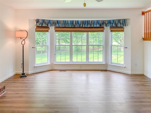 unfurnished room with baseboards, plenty of natural light, and wood finished floors