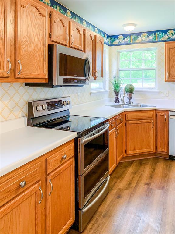 kitchen with stainless steel appliances, wood finished floors, a sink, and light countertops