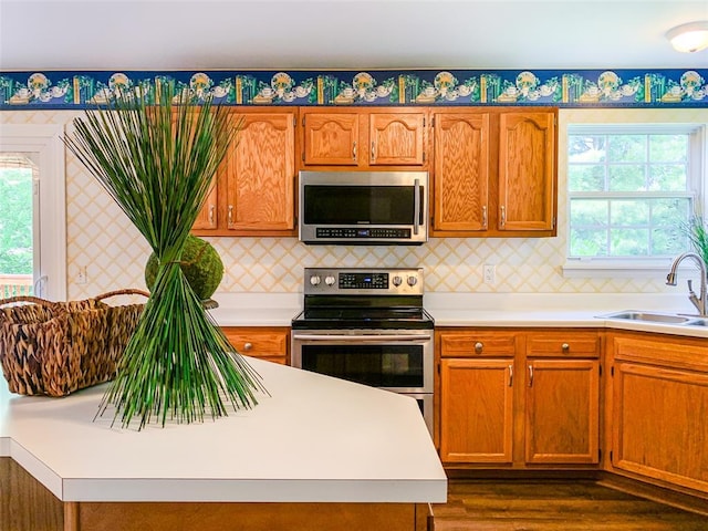 kitchen featuring appliances with stainless steel finishes, a sink, light countertops, and dark wood-style flooring