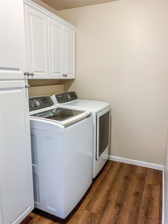 washroom with washing machine and dryer, dark wood finished floors, cabinet space, and baseboards