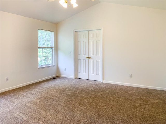 unfurnished bedroom with carpet floors, lofted ceiling, baseboards, and a closet
