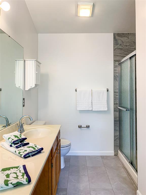 bathroom with a shower stall, vanity, toilet, baseboards, and tile patterned flooring