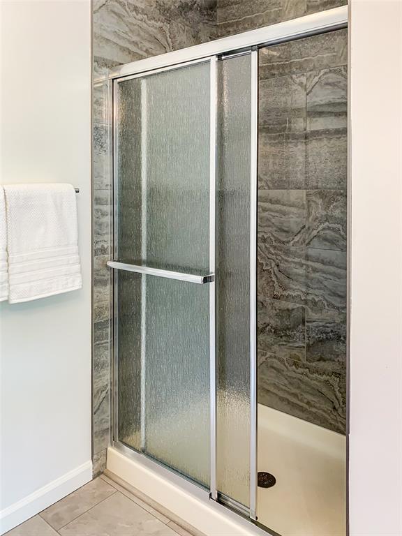 full bath with a shower stall, tile patterned floors, and baseboards