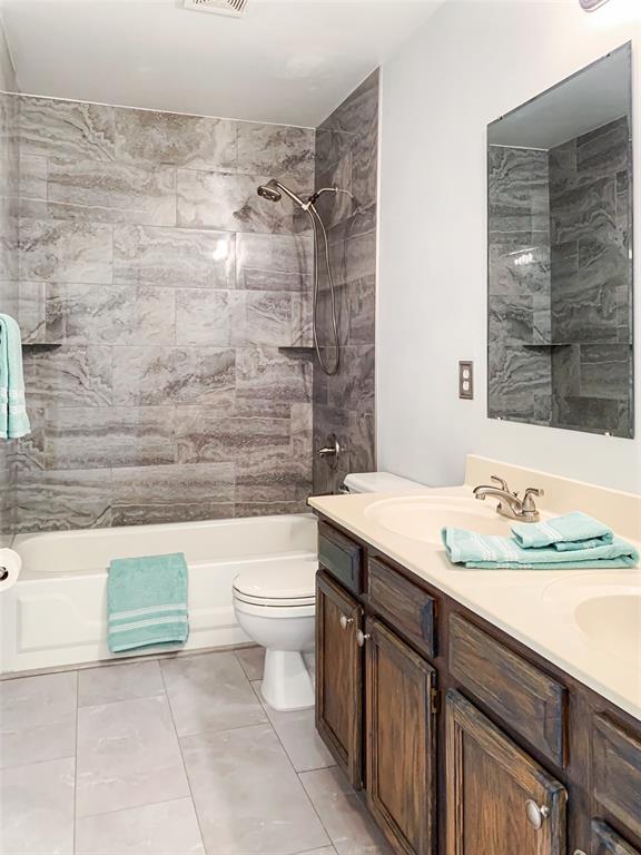 full bathroom featuring toilet, shower / bathtub combination, double vanity, and tile patterned floors