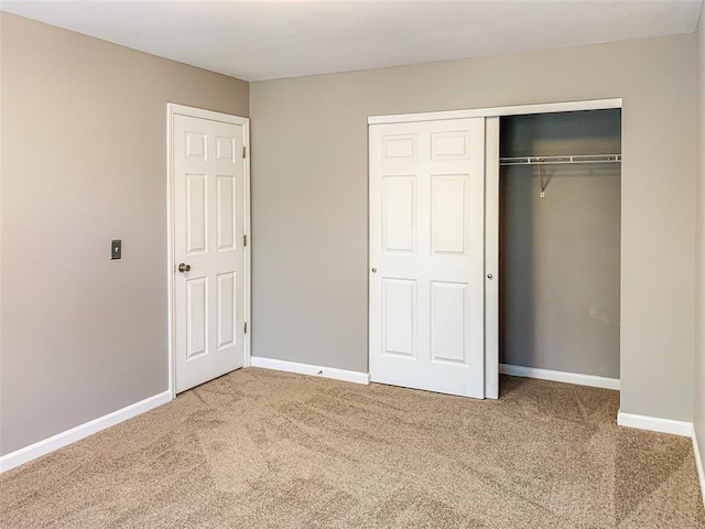 unfurnished bedroom with carpet, a closet, and baseboards